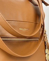 Curved front handle and exterior zippered pocket on cognac pebbled vegan leather with stamped Baldwin Baby Co logo