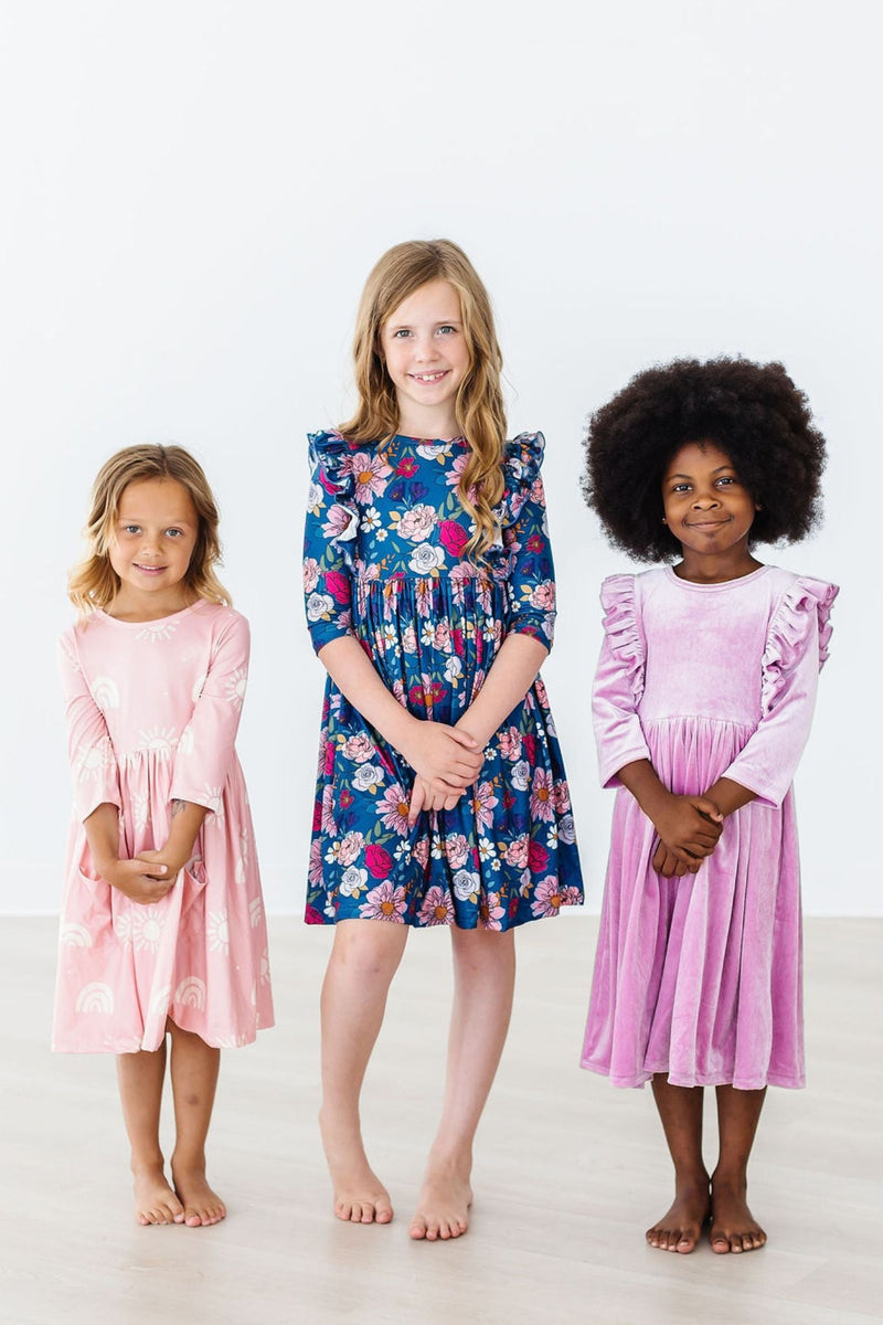 Three young girls wearing colorful dresses, showcasing the Soft Pink Suns 3/4 Sleeve Pocket Twirl Dress by Mila & Rose, perfect for twirling and everyday adventures.