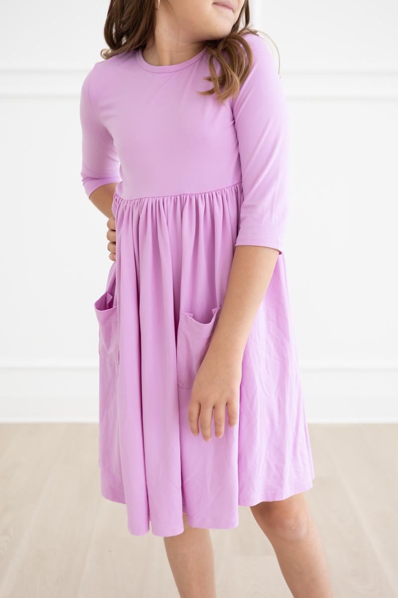 Bright Lilac 3/4 Sleeve Pocket Twirl Dress for Girls displayed on a hanger, showcasing its vibrant color and playful design.