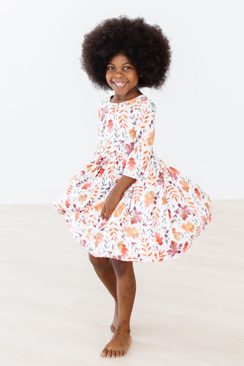 Young girl joyfully twirling in the Falling Leaves 3/4 Sleeve Pocket Twirl Dress by Mila & Rose, showcasing the colorful autumn leaf pattern.