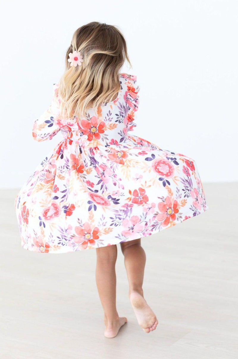 Back view of a girl in the Tangerine Leaves 3/4 Sleeve Ruffle Twirl Dress, twirling gracefully, highlighting the playful skirt design and colorful floral details.