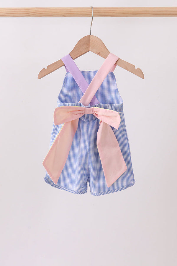 Blue checkered romper with pink ribbon on a hanger against a white background