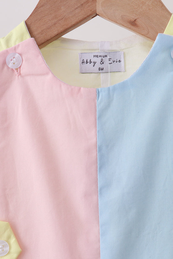 Blue and yellow color-block jonjon with pastel pink panel on a wooden hanger.