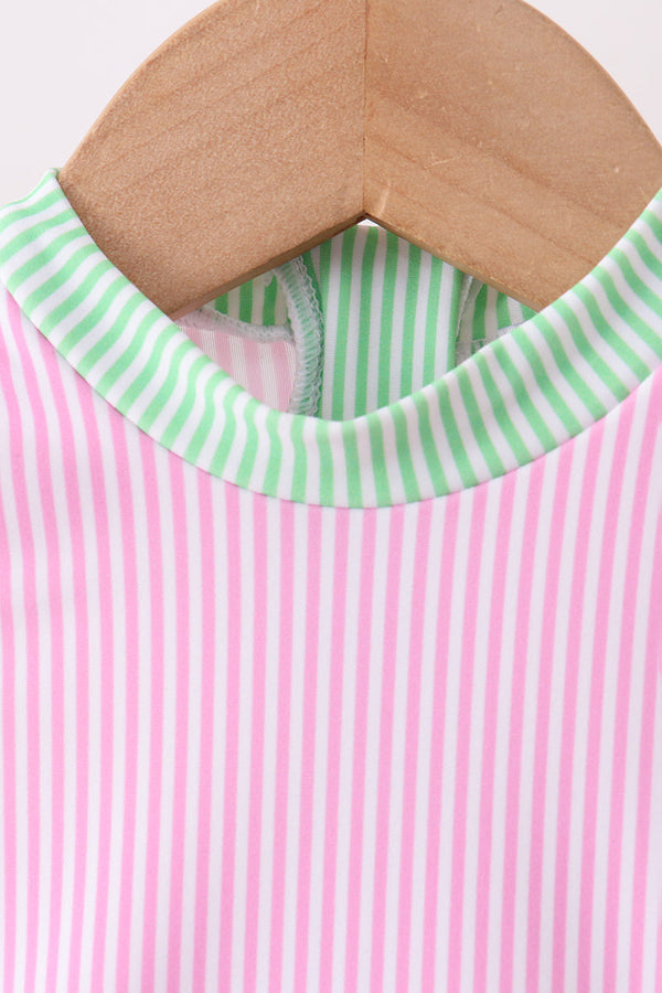 Pink striped rash guard swimsuit with green collar on hanger