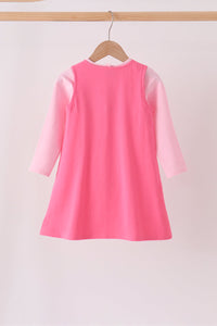 Back view of a pink Jack-O-Lantern applique 2pc dress set featuring a dark pink sleeveless tunic over a light pink long-sleeve shirt on a wooden hanger.