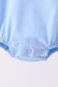 Close-up of light blue baby bubble set leg with elastic trim and three snap buttons for easy diaper changes.
