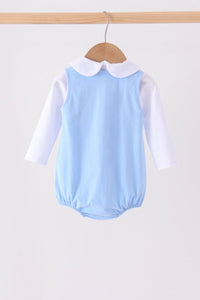 Back of light blue Jack-O-Lantern applique bubble set with white collar and long sleeves hanging on a wooden hanger.