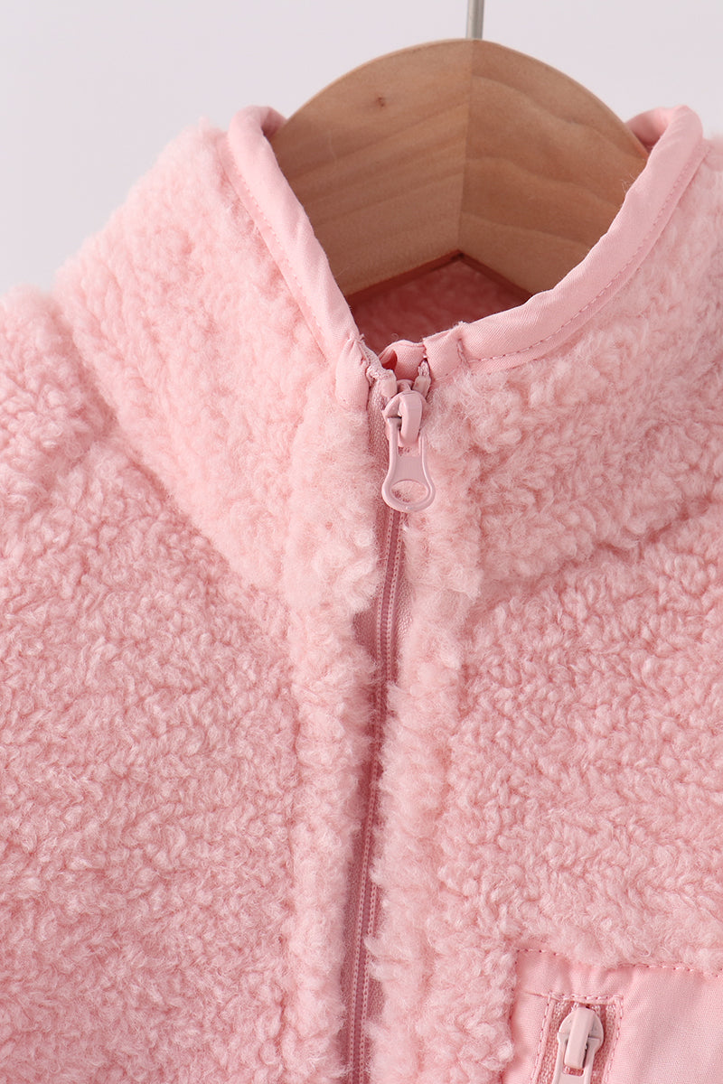 Soft pink fleece zip-up jacket with a matching zipper pull, displayed on a wooden hanger for cozy layering.