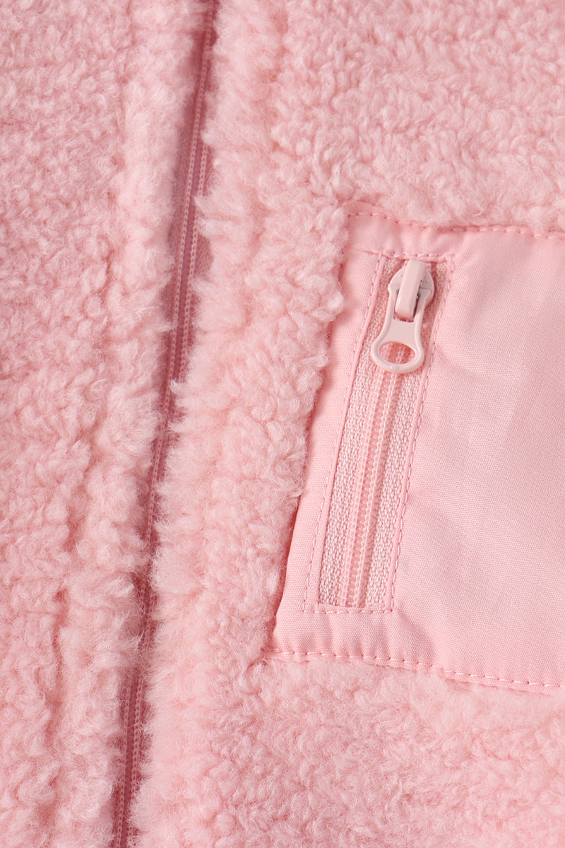 Soft pink fleece jacket close-up showing fluffy texture and matching zippered pocket for cozy layering.