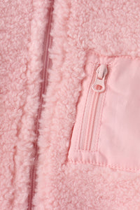 Soft pink fleece jacket close-up showing fluffy texture and matching zippered pocket for cozy layering.