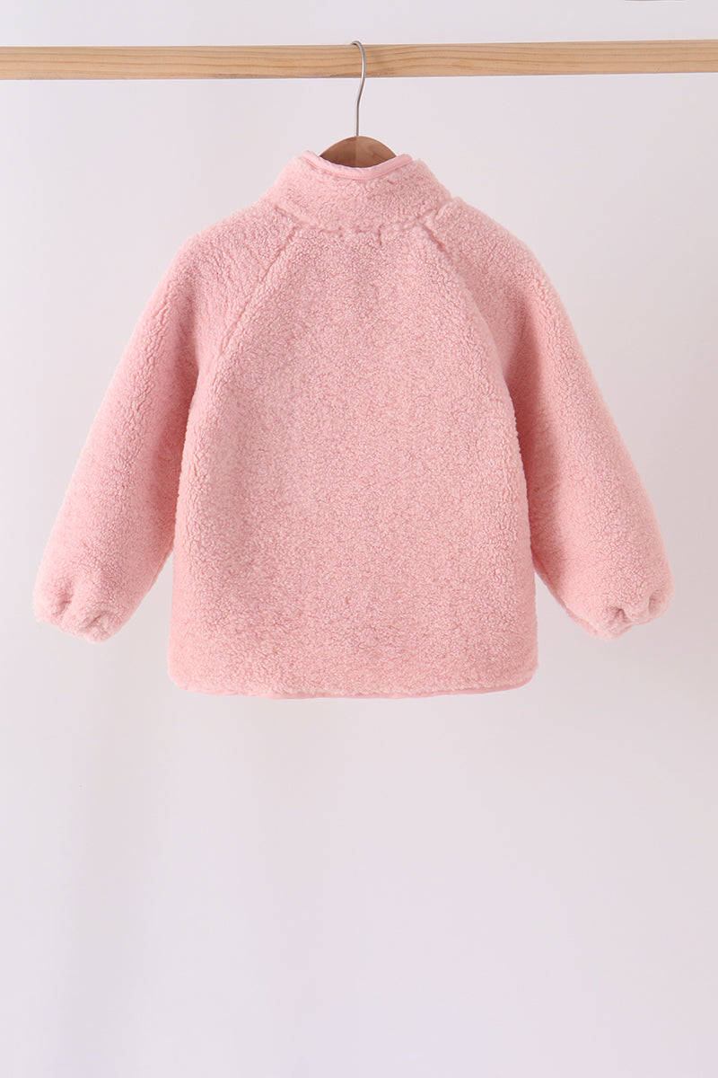 Back view of a soft pink fleece zipper jacket with a high collar and elastic cuffs, hanging on a wooden hanger.