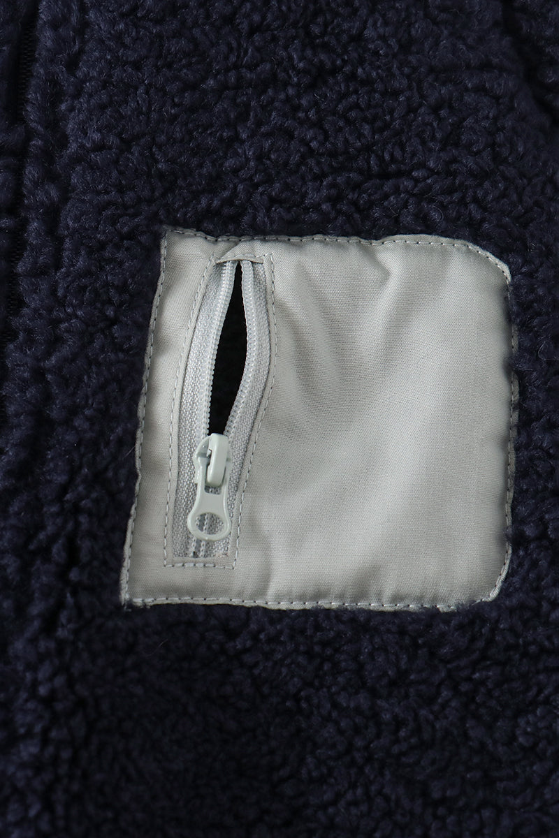 Navy fleece jacket close-up showing soft textured fabric and secure light gray zippered pocket for safe storage.