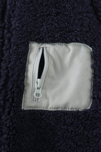 Navy fleece jacket close-up showing soft textured fabric and secure light gray zippered pocket for safe storage.