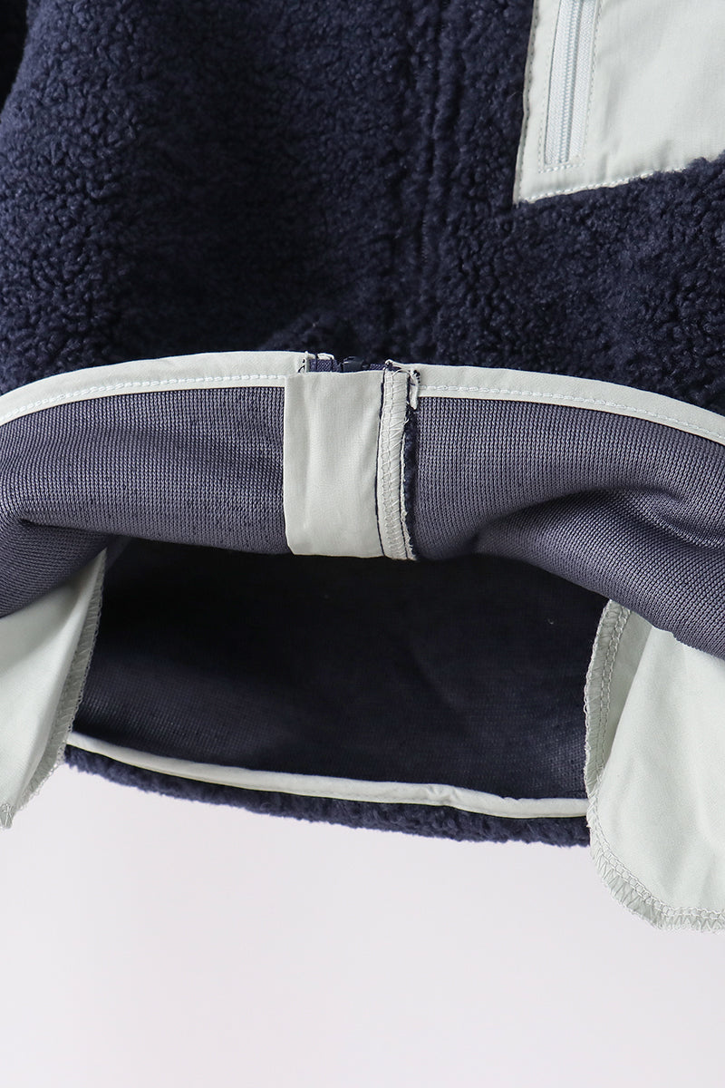 Navy fleece zipper jacket hem showing soft texture, light trim, and ribbed inner lining for cozy layering.