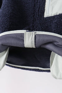 Navy fleece zipper jacket hem showing soft texture, light trim, and ribbed inner lining for cozy layering.