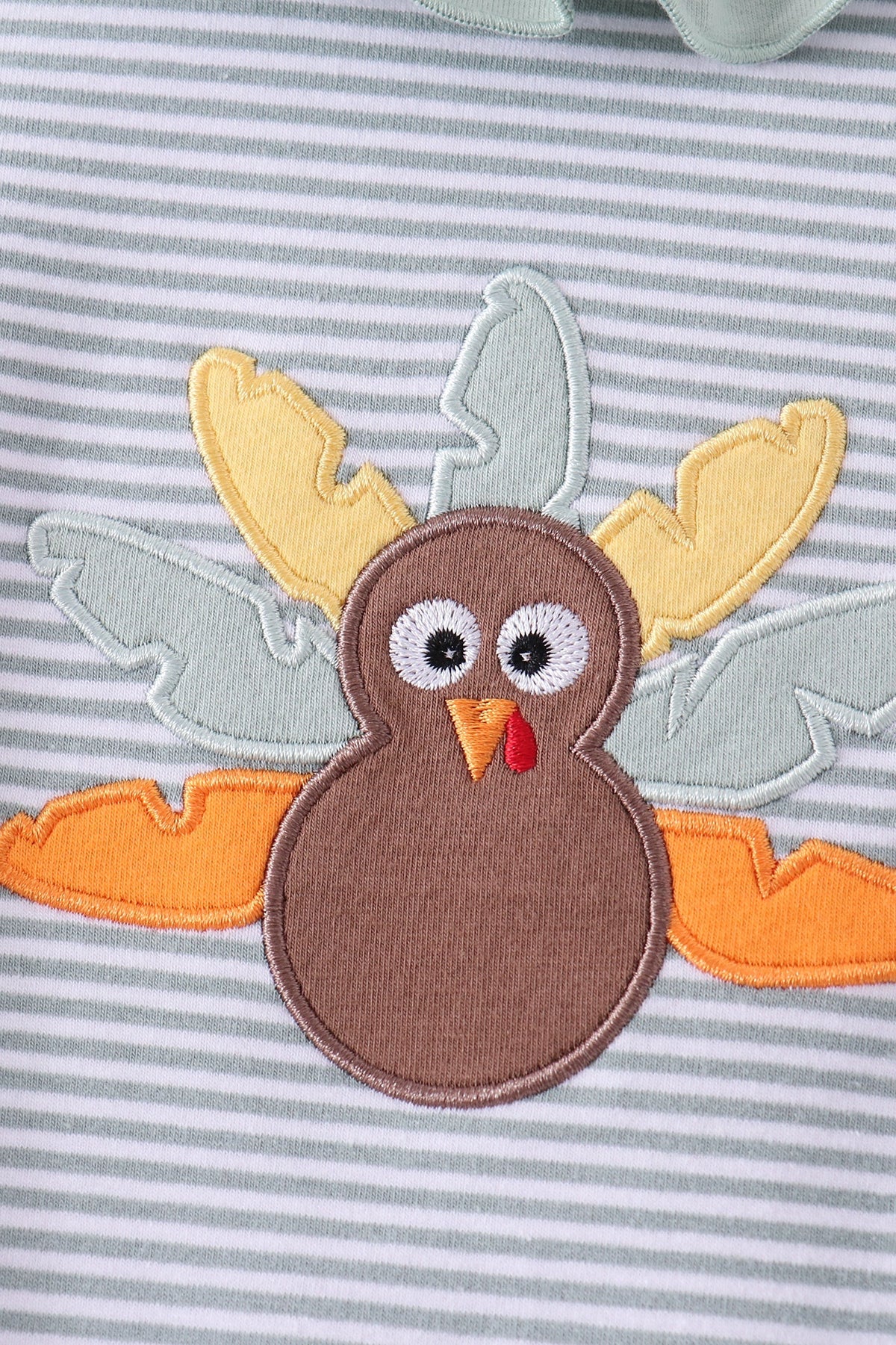 A close-up of a turkey applique patch sewn onto a gray and white striped fabric garment.