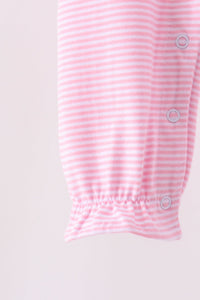 Close-up of a baby garment sleeve with horizontal pink and white stripes, elasticized cuff, and three light blue snap buttons.