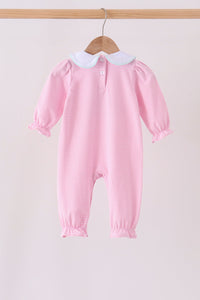 A pink and white striped baby jumpsuit with a white Peter Pan collar, hanging on a wooden hanger from a light wood rod against a pale pink background.