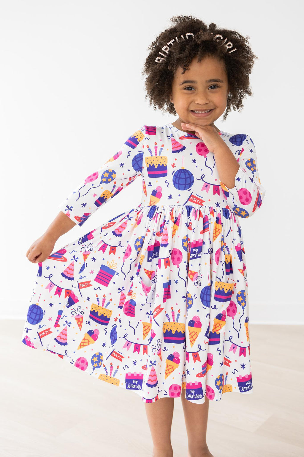 Joyful child twirling in a Happy Birthday 3/4 Sleeve Pocket Twirl Dress adorned with festive party patterns, celebrating her special day in style.