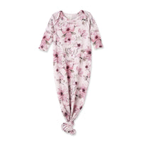 A baby footed sleeper with long sleeves and a knotted ankle, featuring a pink and purple floral pattern on a pale pink background.
