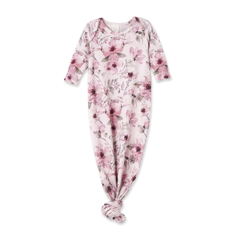 A baby footed sleeper with long sleeves and a knotted ankle, featuring a pink and purple floral pattern on a pale pink background.
