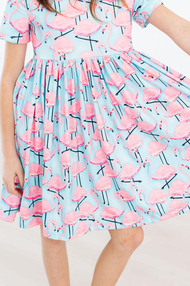 Close-up of the Pretty in Pink Flamingos S/S Pocket Twirl Dress, showcasing the charming flamingo pattern and full skirt, ideal for expressive playtime.