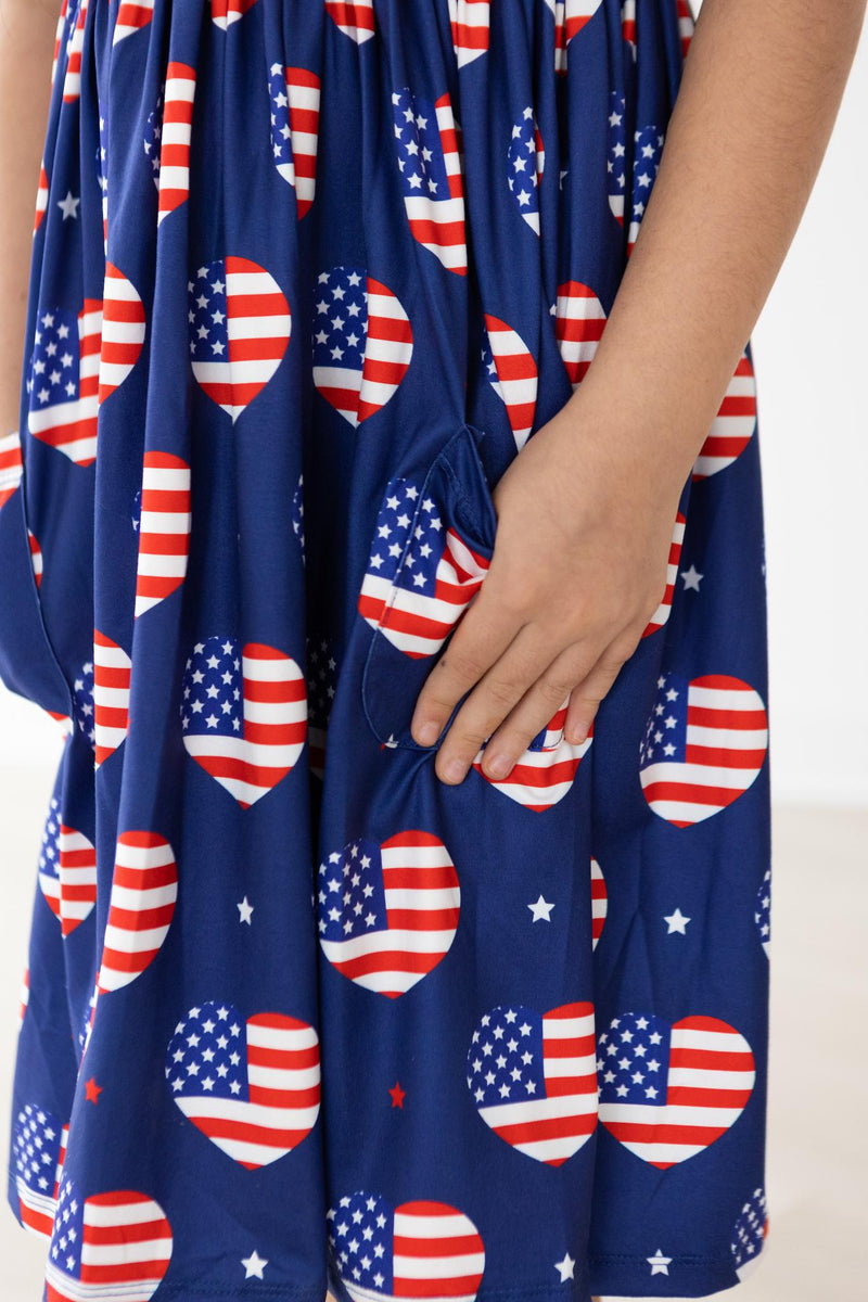 Close-up of the 'I Heart the USA' Short Sleeve Pocket Twirl Dress for Girls, highlighting the playful pocket design and vibrant heart patterns decorated with American flags.
