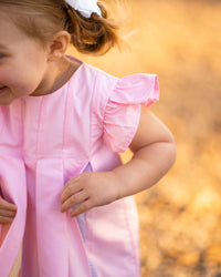 Pink rainbow dress for girls featuring flutter sleeves and pleated front. Perfect swing dress for parties or twirling.