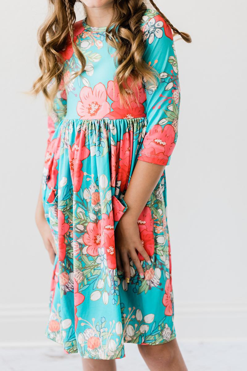 Close-up of a girl wearing the After the Rain 3/4 Sleeve Pocket Twirl Dress, emphasizing the bright colors and playful design, making it a charming twirl dress for girls.