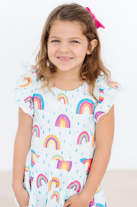 Little girl wearing April Showers Short Sleeve Twirl Leotard with rainbow raindrop pattern, smiling.