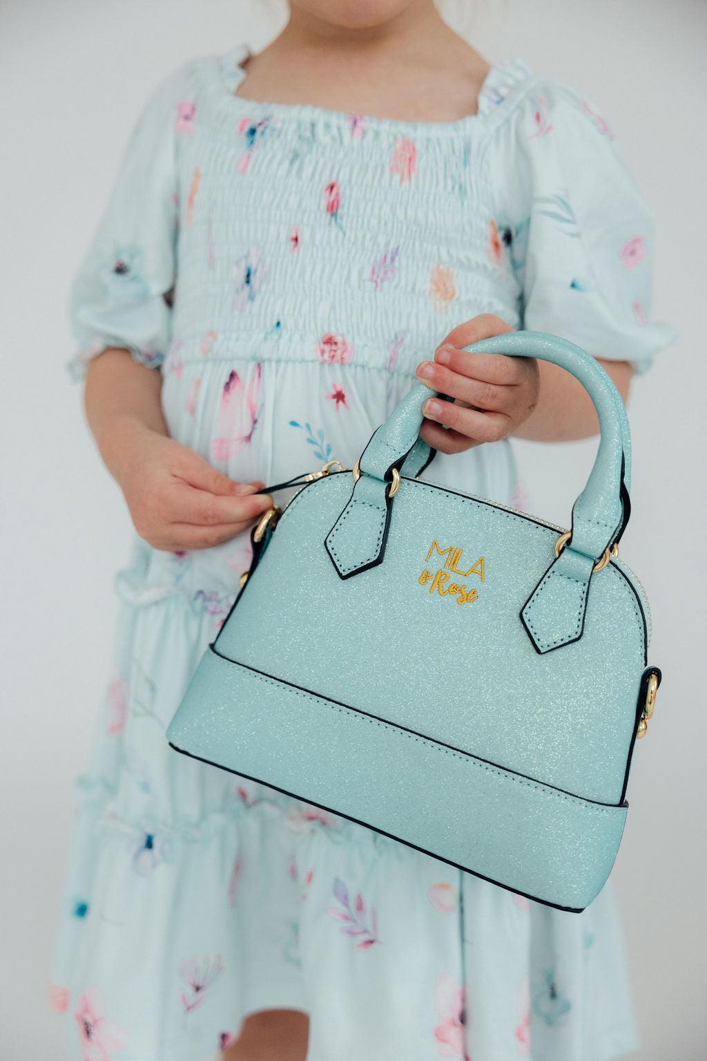 Child holding aqua glitter girl's crossbody purse with gold hardware. Perfect fashion accessory or gift for little fashionistas.