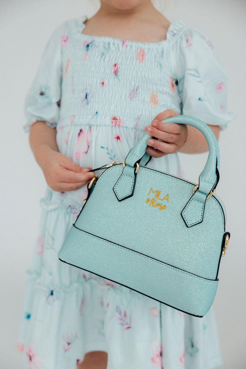 Child holding aqua glitter girl's crossbody purse with gold hardware. Perfect fashion accessory or gift for little fashionistas.