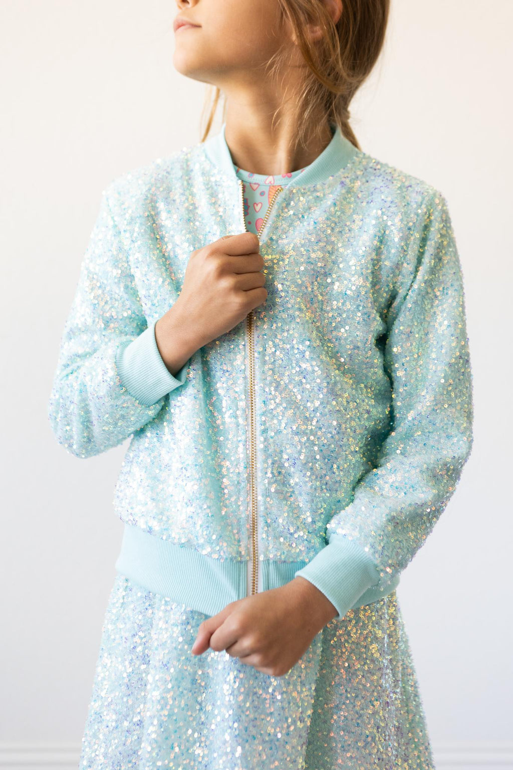 Aqua Sequin Jacket for Girls showcased on a model, featuring shimmering sequins in a vibrant aqua color, perfect for adding sparkle to any outfit.
