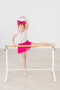 Tiny ballerina in Ballerina Bows Short Sleeve Twirl Leotard with pink bow at a ballet barre.