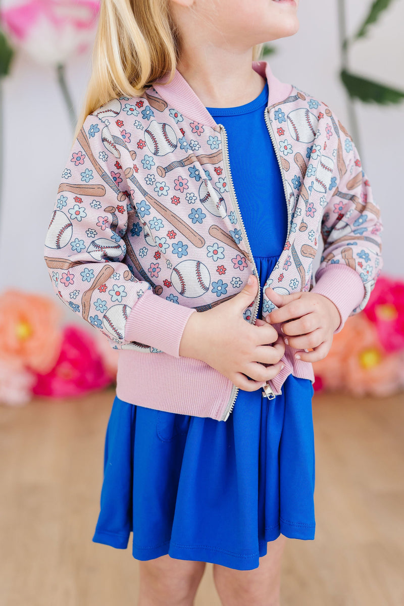 Child wearing the Batter Up Shimmer Jacket, twirling joyfully with a sparkling smile, highlighting the jacket's stylish and fun appeal.