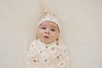Baby wearing GOTS certified organic cotton knotted hat with checkered bear print, swaddled in matching blanket.