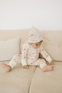 Baby wearing GOTS certified organic cotton knotted hat with checkered bear pattern in soft pink.