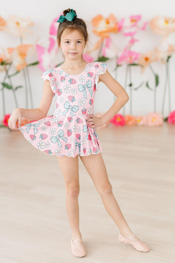 Berry Picnic Short Sleeve Twirl Leotard worn by a young dancer in pink print with strawberries, flowers, and bows.