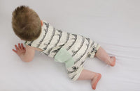 Baby crawling in GOTS certified organic cotton sleeveless romper with grass print and mint green pocket. Chemical-free baby fashion.