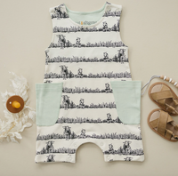 GOTS certified organic cotton sleeveless romper with black animal print and mint green patches, styled with leather sandals and a wooden pacifier clip.