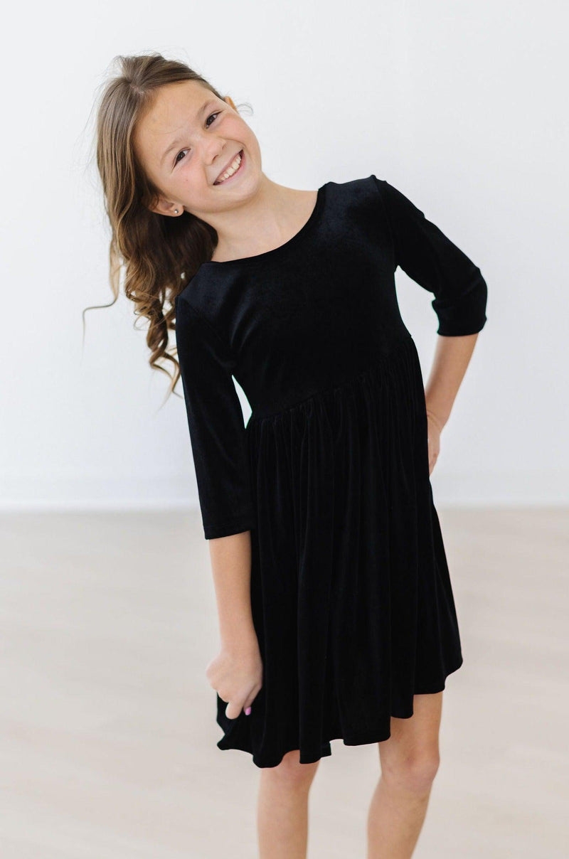 Cheerful girl playfully posing in the SALE Black Velvet Twirl Dress by Mila & Rose®, exuding confidence and charm.