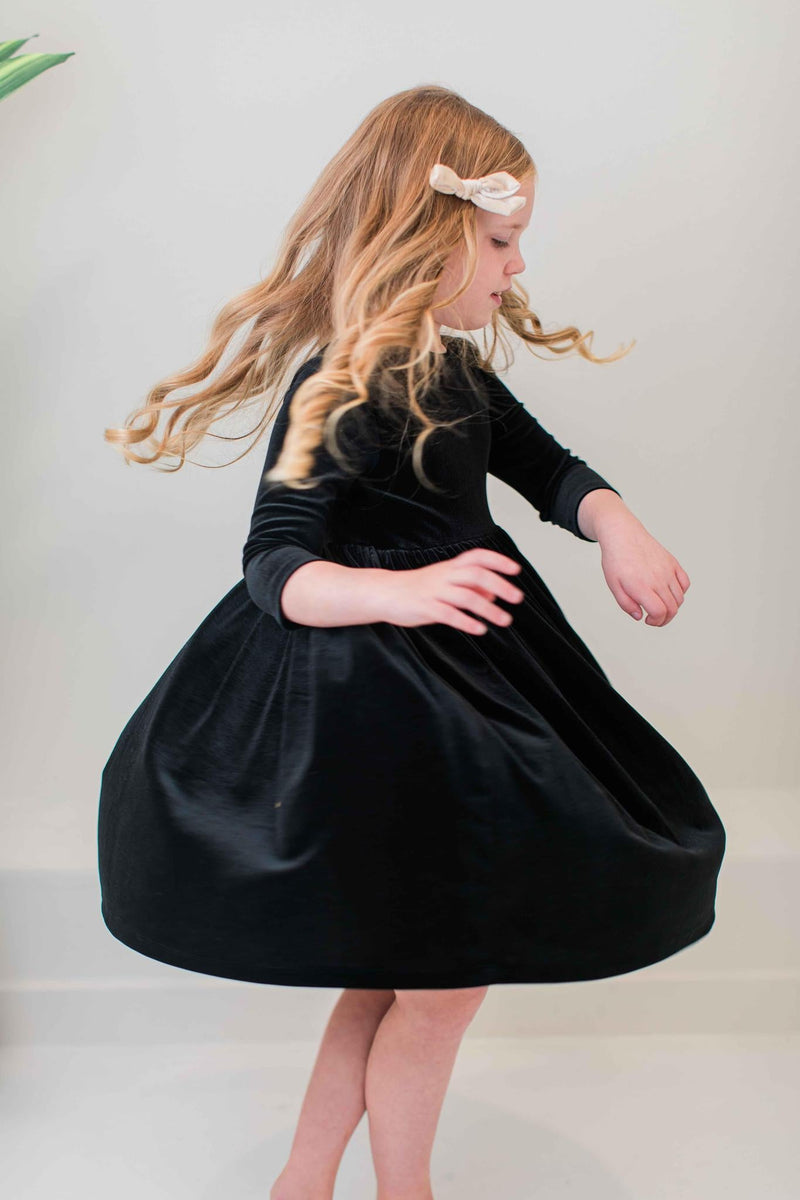 Girl spinning gracefully in the SALE Black Velvet Twirl Dress from Mila & Rose®, showing off the dress's luxurious velvet fabric and twirl appeal.