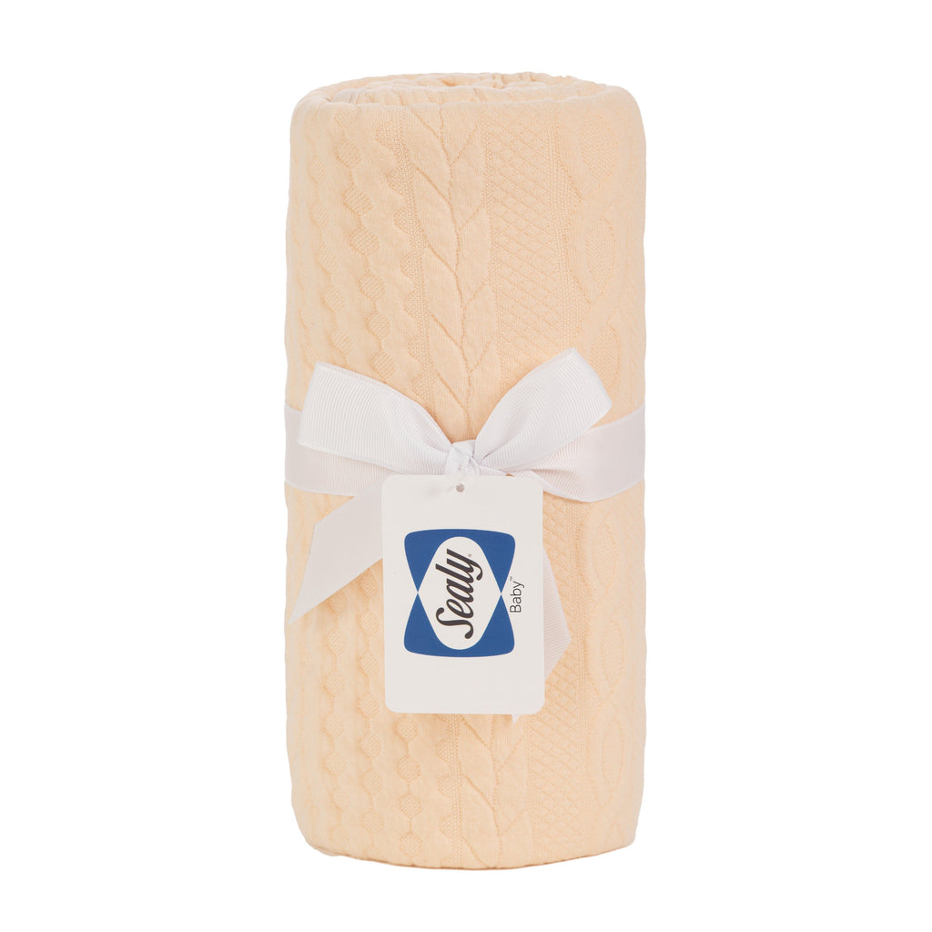 Sealy Baby Knit Blanket in Camel Sand color, elegantly rolled and tied with a white ribbon, showcasing its soft texture, perfect for newborns.