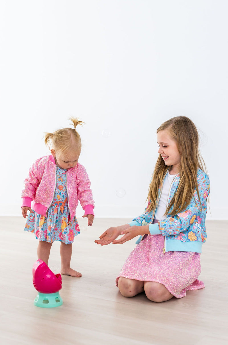 The Blue Retro Unicorns Satin Jacket styled with a twirl dress, perfect for casual or chic occasions.
