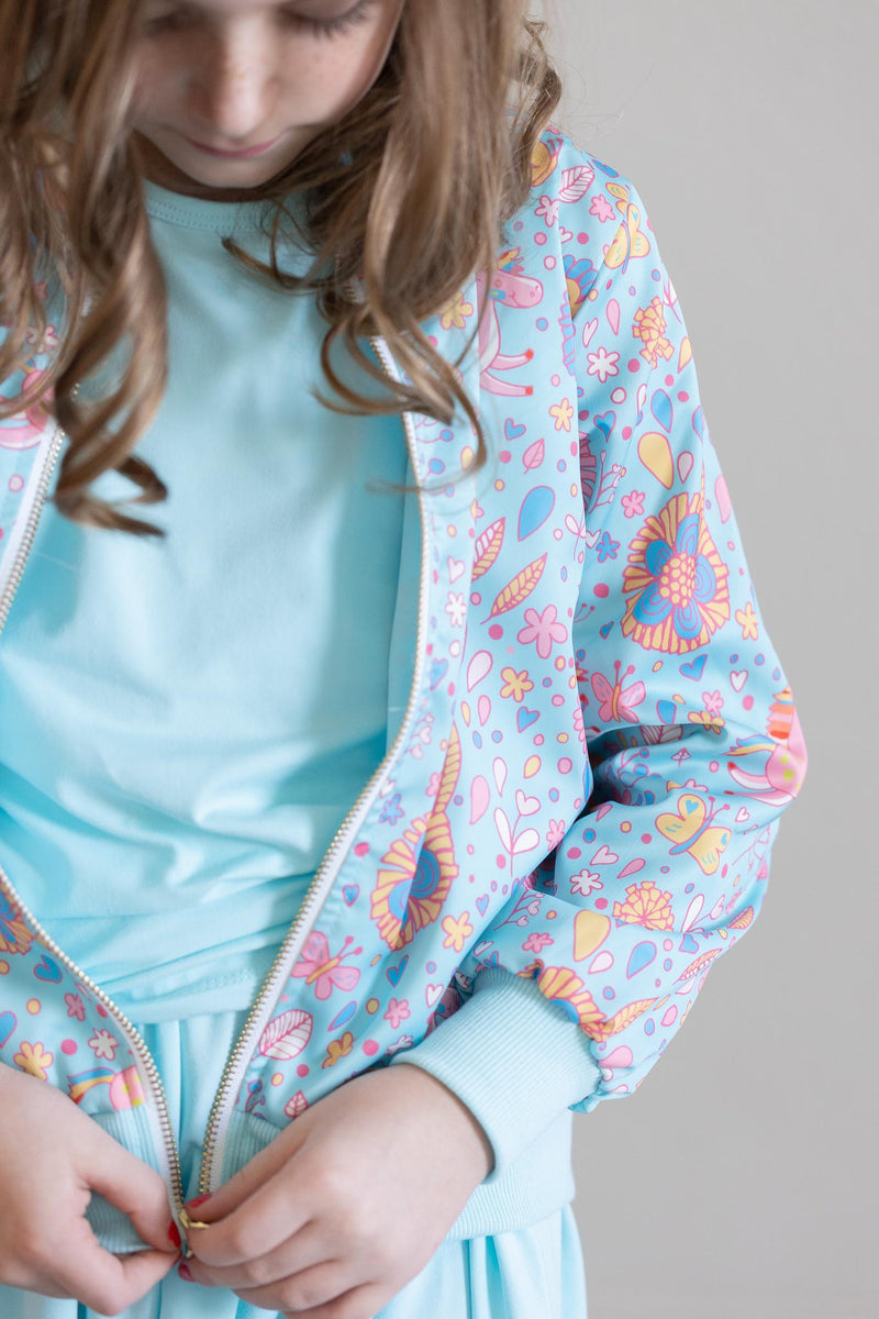 Styled look of the Blue Retro Unicorns Satin Jacket by Mila & Rose paired with a twirl dress, highlighting its versatility and trendy design for casual and chic occasions.