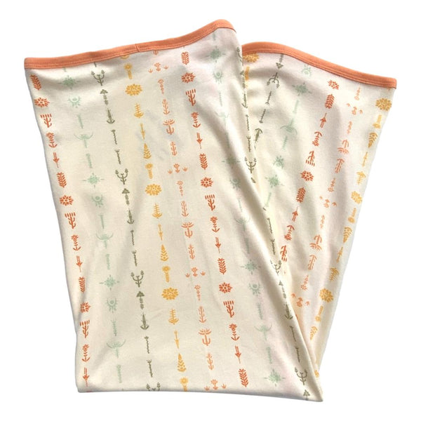 GOTS certified organic cotton baby blanket featuring a boho floral print with warm orange accents and soft trim.