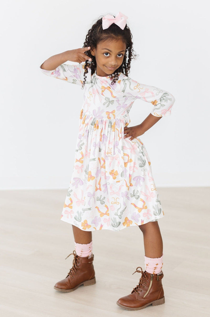 Child enjoying playtime in the Boho Bows 3/4 Sleeve Pocket Twirl Dress, demonstrating versatility for various occasions.
