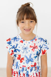 Smiling child in Born to Sparkle Flutter Sleeve Twirl Dress featuring a star and bow print.