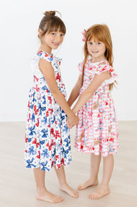 Two girls wear Born to Sparkle Flutter Sleeve Twirl Dresses, blue bow print and pink carnival print, twirl-ready.