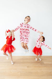 Three girls wearing Bow La La Long Sleeve Pocket Twirl Dress in pink bow-print twirl style, jumping with joy.